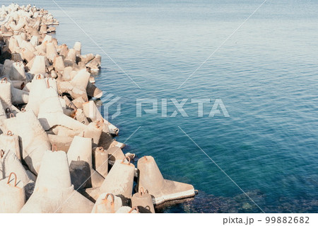 Coast breakwaters protecting from large waves with sea water background. The seashore is reinforced with concrete tetrapods. 99882682
