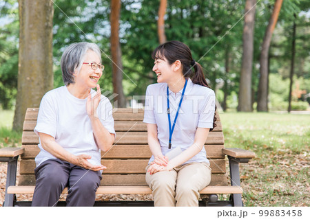 公園で話す高齢者と笑顔の介護スタッフの女性(話す・楽しい) 公園で話す高齢者と笑顔の介護スタッフの女性(話す・楽しい) 99883458