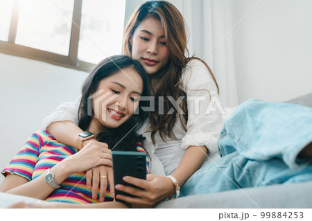 lgbtq, lgbt concept, homosexuality, portrait of two asian women enjoying together and showing love for each other while using smartphone mobile to take selfies. lgbtq, lgbt concept, homosexuality, portrait of two asian women enjoying together and showing love for each other while using smartphone mobile to take selfies. 99884253