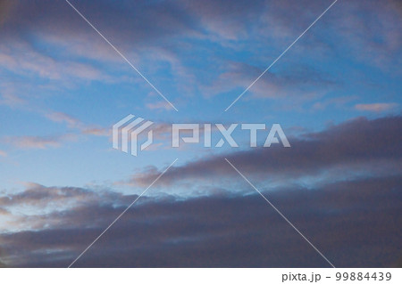 都会の空に広がる夕焼けが始まりグレーの分厚い雲がピンクに染まる青空（東京都千代田区） 99884439