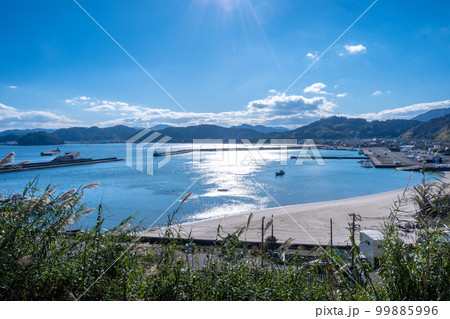 晴れた日の大堂津港に浮かぶ一隻の漁船と大堂津海水浴場 99885996