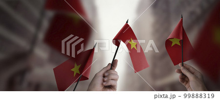 A group of people holding small flags of the Vietnam in their hands A group of people holding small flags of the Vietnam in their hands 99888319