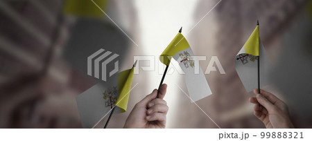 A group of people holding small flags of the Vatican in their hands 99888321