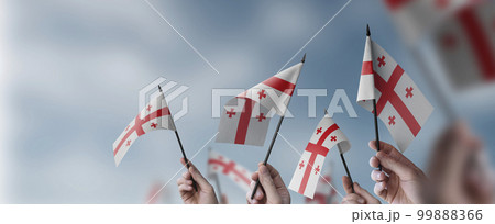 A group of people holding small flags of the Georgia in their hands A group of people holding small flags of the Georgia in their hands 99888366