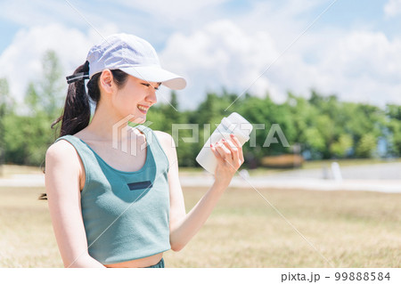 公園でトレーニングしながらプロテインを飲む女性 公園でトレーニングしながらプロテインを飲む女性 99888584