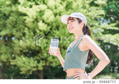 公園でトレーニングしながらプロテインを飲む女性 公園でトレーニングしながらプロテインを飲む女性 99888755