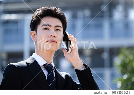 オフィス街で電話をする若いビジネスマン 新卒や新社会人のイメージに オフィス街で電話をする若いビジネスマン 新卒や新社会人のイメージに 99889622