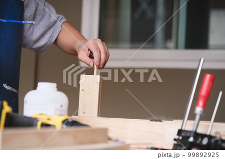 Woodworking operators are using glue to put together the wood parts to assemble and build a wooden table for their customers. Woodworking operators are using glue to put together the wood parts to assemble and build a wooden table for their customers. 99892925
