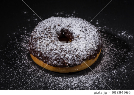 Sprinkling sugar powder on chocolate donut Sprinkling sugar powder on chocolate donut 99894966