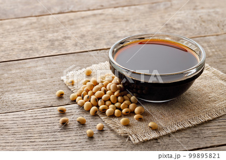 soy sauce in glass bowl with dry soybeans on wooden table 99895821