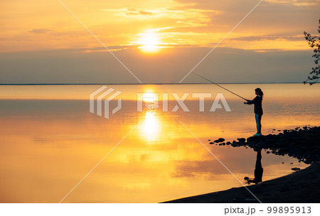 Woman fishing on Fishing rod spinning at sunset background. 99895913