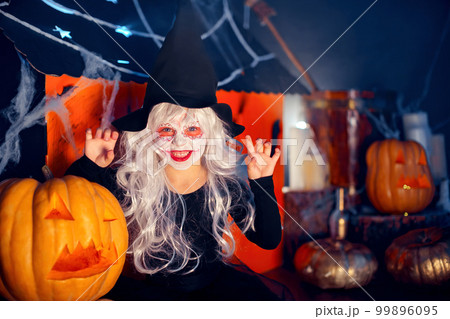 Little girls in witches carnival costume scaring and making faces on background decor Halloween Little girls in witches carnival costume scaring and making faces on background decor Halloween 99896095