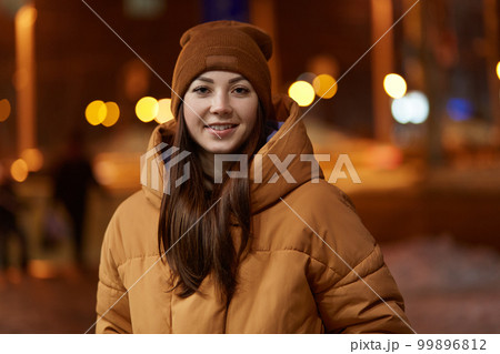 Positive satisfied young Caucasian woman smiles broadly, being pleased, going to have date with boyfriend and outdoor stoll during evening, wears fashionable outer clothing. Leisure concept. Positive satisfied young Caucasian woman smiles broadly, being pleased, going to have date with boyfriend and outdoor stoll during evening, wears fashionable outer clothing. Leisure concept. 99896812