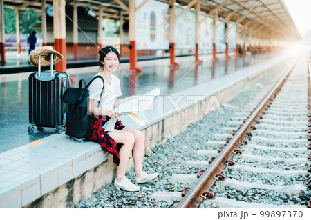 summer, relax, vacation, travel, portrait of a cute Asian girl looking at a map to plan a trip while waiting at the train station summer, relax, vacation, travel, portrait of a cute Asian girl looking at a map to plan a trip while waiting at the train station 99897370