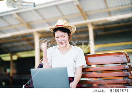 summer, relax, vacation, travel, portrait of beautiful Asian girl using the computer laptop at the train station while waiting for their travel time 99897371