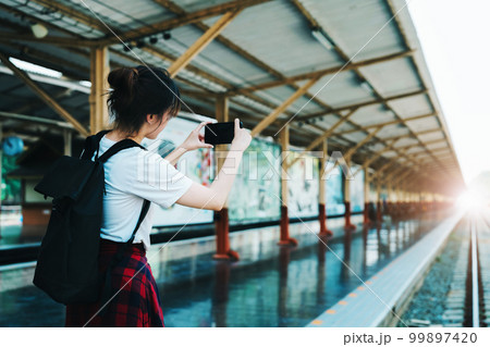 summer, relax, vacation, travel, portrait of beautiful Asian girl using the smartphone mobile take a photo at the train station while waiting for their travel time summer, relax, vacation, travel, portrait of beautiful Asian girl using the smartphone mobile take a photo at the train station while waiting for their travel time 99897420