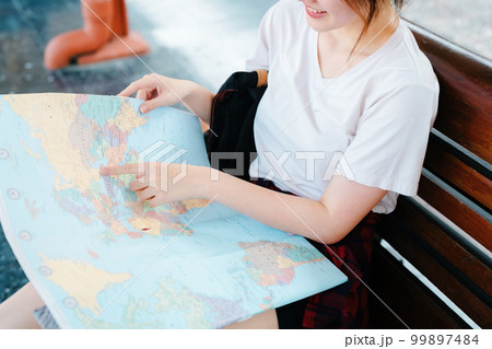 summer, relax, vacation, travel, portrait of a cute Asian girl looking at a map to plan a trip while waiting at the train station summer, relax, vacation, travel, portrait of a cute Asian girl looking at a map to plan a trip while waiting at the train station 99897484
