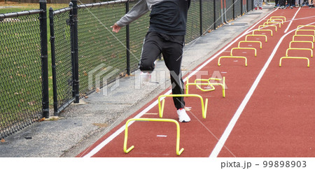 Runner tripping over yellow mini hurdles in lane on a track 99898903