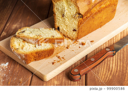 Sliced homemade cupcake with raisins sprinkled with powdered sugar on a wooden cutting board and knife Sliced homemade cupcake with raisins sprinkled with powdered sugar on a wooden cutting board and knife 99900586