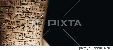 A stone tablet engraved with ancient Egyptian hieroglyphic symbols against a dark black background with copy space 99901670
