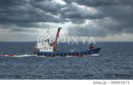 A longliner fishing boat in the open sea against a dramatic overcast sky above the horizon A longliner fishing boat in the open sea against a dramatic overcast sky above the horizon 99901673