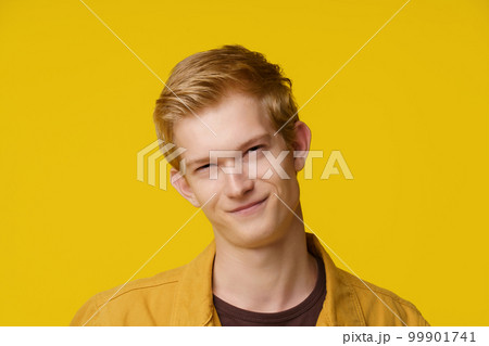 Emotion of Cunning and Deception Concept. A European Young Man shows an Emotion of Cunning and Distrust on a Yellow Background. High quality photo 99901741