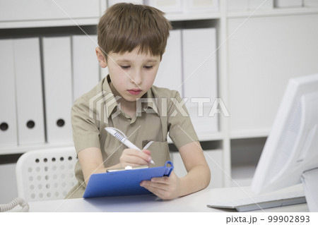 Junior school student does his homework. A boy with a pen in his hands writes something. A child solves a problem 99902893