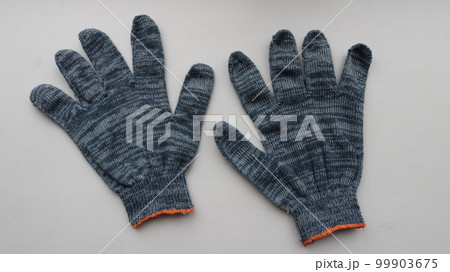 two fabric work gloves made of gray-black material isolated on a light surface, protective cotton gloves intended for manual work close-up 99903675