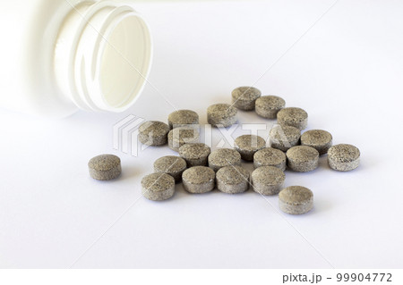 Round brown tablets with spots on a white background scattered near the jar. Iron supplements. Health medications 99904772