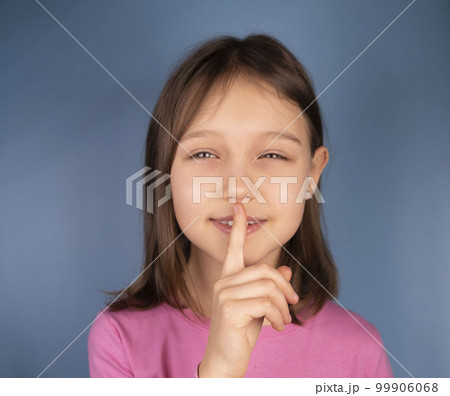 girl showing a finger at her closed mouth, a symbol or sign of silence or quiet. High quality photo 99906068