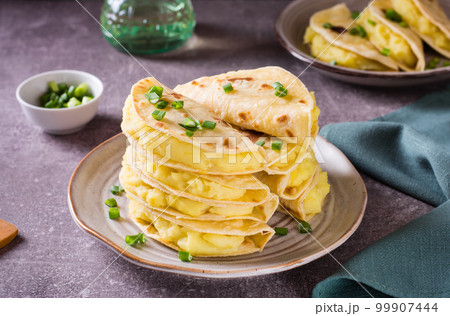 A stack of Kystyby - thin flatbread filled with mashed potatoes and onions on a plate. 99907444