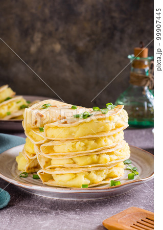 Kystyby - a thin flatbread filled with mashed potatoes and onions on a plate. Vertical view 99907445
