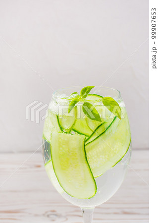 Refreshing water with slices of cucumber and basil leaves in a glass 99907653