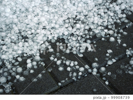 hailstones after a storm on a concrete pavement 99908739