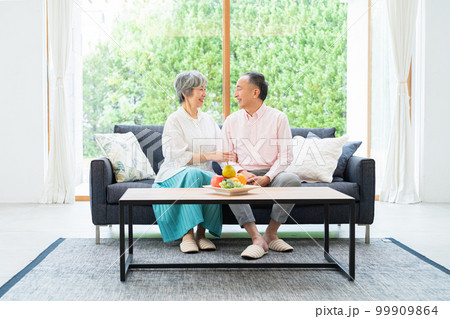 ソファでくつろぐシニア夫婦 99909864