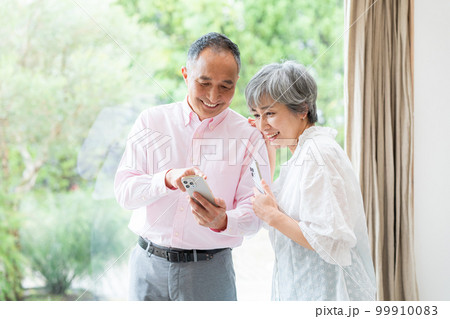 スマホを持つシニア夫婦 スマホを持つシニア夫婦 99910083
