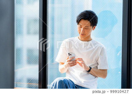 スマホを操作する若い男性 スマホを操作する若い男性 99910427