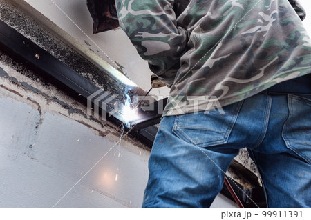 The welder is welding the steel structure to add to the house. The welder is welding the steel structure to add to the house. 99911391