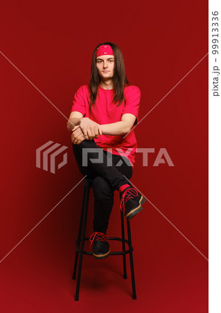 Man sits on high chair with his leg on his leg Man sits on high chair with his leg on his leg 99913336