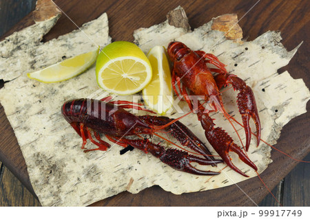 boiled craw fish on kitchen board with net and lemon slices closeup photo boiled craw fish on kitchen board with net and lemon slices closeup photo 99917749
