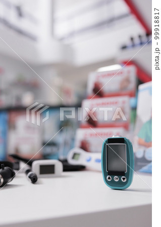Medical glucometer standing on table ready to measure customers glucose and insulin level in drugstore. Empty pharmacy filled with pharmaceutical products and vitamins. Health care service and concept Medical glucometer standing on table ready to measure customers glucose and insulin level in drugstore. Empty pharmacy filled with pharmaceutical products and vitamins. Health care service and concept 99918817
