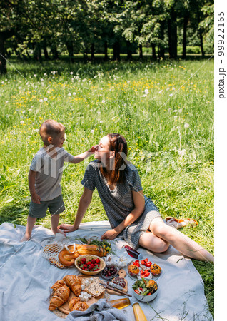 Family mom and son on picnic. Smiling and enjoying summer on blanket in park. Family mom and son on picnic. Smiling and enjoying summer on blanket in park. 99922165