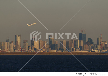 東京高層ビル群を背に離陸する飛行機 99923666
