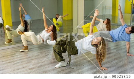 Teenagers dancing hip-hop in studio, learn dance moves together, wearing stylish outfit 99925319