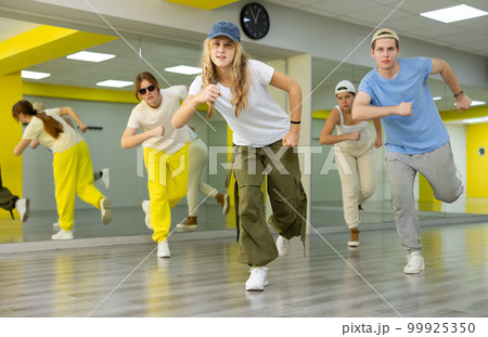 Teenage girl in cap training breakdance Toprock moves in dance hall Teenage girl in cap training breakdance Toprock moves in dance hall 99925350