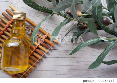 bottle of olive oil and olive leaves on yellow  99932541