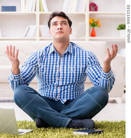 Young handsome man sitting on floor at home Young handsome man sitting on floor at home 99933588