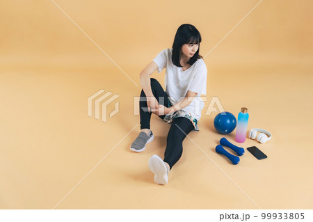 座る女性とトレーニング用品　フィットネスジム　エクササイズ 99933805