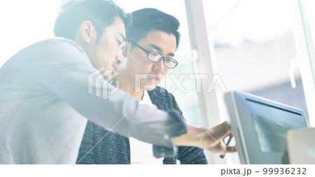 two young asian corporate executives working together using desktop computer 99936232