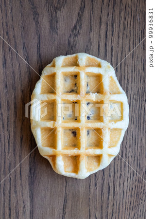 Delicious fresh waffle with chocolate filling lies on a wooden table. vertical photo 99936831
